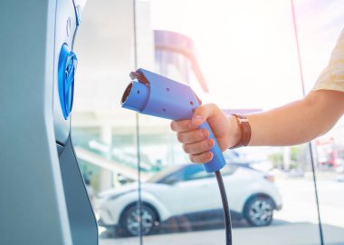 Man charge his electric car at city charging station.
