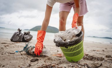 Kadın bir çevre bilimci plastikten ve diğer atıklardan sahil kenarını temizliyor..