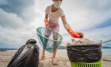 Kadın bir çevre bilimci plastikten ve diğer atıklardan sahil kenarını temizliyor..