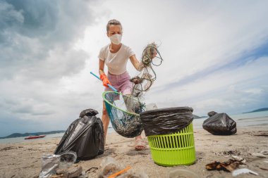 Kadın bir çevre bilimci plastikten ve diğer atıklardan sahil kenarını temizliyor..