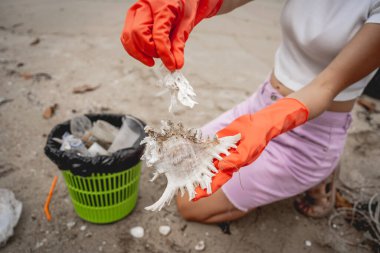 Kadın bir çevre bilimci plastikten ve diğer atıklardan sahil kenarını temizliyor..