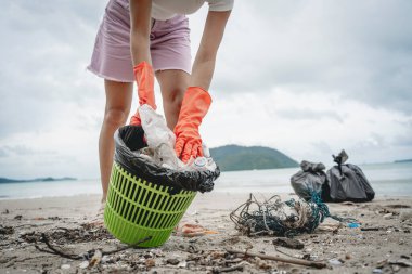 Kadın bir çevre bilimci plastikten ve diğer atıklardan sahil kenarını temizliyor..