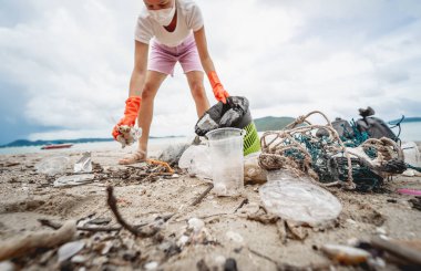 Kadın bir çevre bilimci plastikten ve diğer atıklardan sahil kenarını temizliyor..