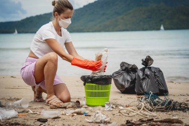 Kadın bir çevre bilimci plastikten ve diğer atıklardan sahil kenarını temizliyor..