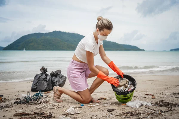 Kadın bir çevre bilimci plastikten ve diğer atıklardan sahil kenarını temizliyor..