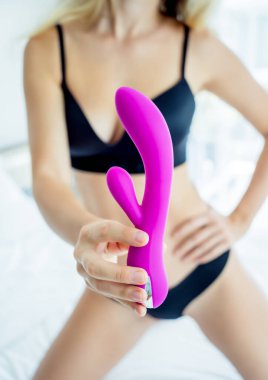 Genç seksi kadın elinde yetişkinler için bir seks oyuncağı tutuyor..
