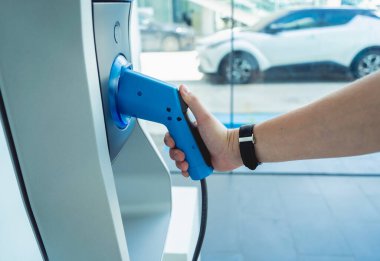 Man charge his electric car at city charging station.