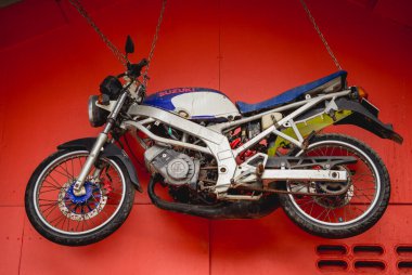 Spor motosikleti kırmızı duvarda asılı..