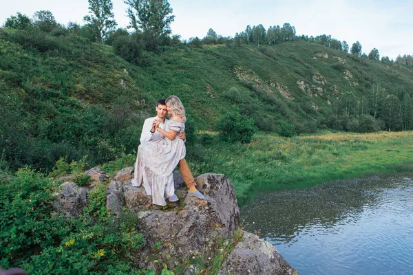 Romantyczna niekochana para siedząca na skałach nad rzeką. — Zdjęcie stockowe
