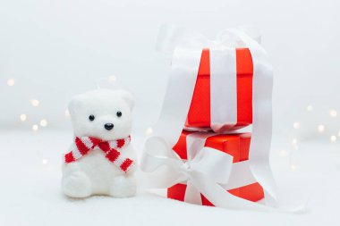 Atkılı beyaz kutup ayısı oyuncağı ve beyaz arka planda beyaz kurdeleli kırmızı hediye kutuları. Noel konsepti.