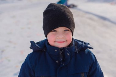 Sıcak giysiler içinde pembe yanakları olan mutlu bir çocuğun kış portresi.