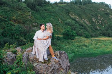 Nehir kenarındaki kayalarda oturan güzel, sevilmeyen bir çift. Boşluğu kopyala.