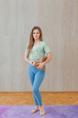 Mavi taytlı ve tişörtlü beyaz bir kadın evde yoga külçeleriyle yoga yapıyor. Fitness ve sağlıklı yaşam tarzı konsepti.
