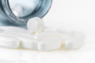 Plastik bir ilaç şişesinden haplar ve haplar dökülüyor, makro görüş.