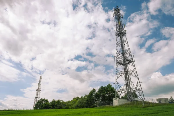 Telecommunications tower on green field with cloudy sky