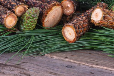 Tahta masanın üzerinde taze kozalaklı çam dalları var.