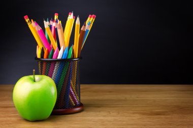 Pencils and apple on table