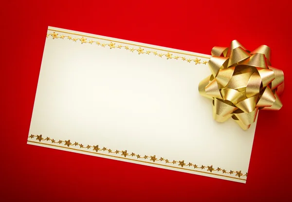 Tarjeta de felicitación sobre papel rojo con lazo dorado —  Fotos de Stock