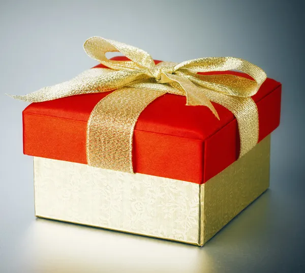 Золотая подарочная коробка на серебряном фоне — стоковое фото