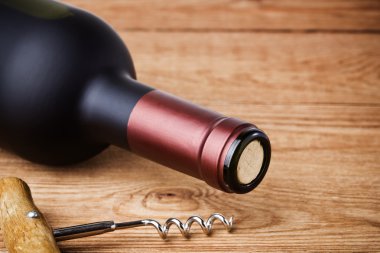 Ahşap arka planda tirbuşonlu bir şişe şarap.