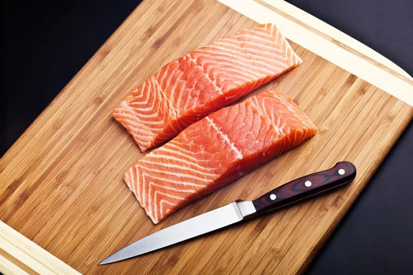 Zalmfilet met mes op een houten bord — Stockfoto