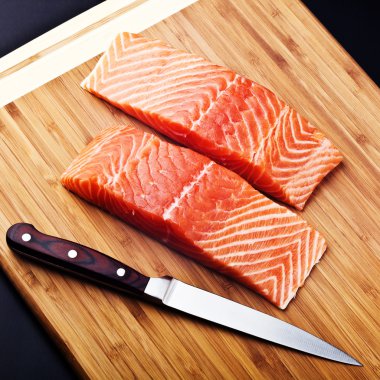 Salmon fillet with knife on wood board clipart