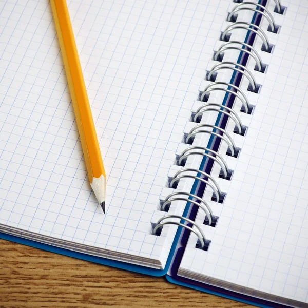 Lápis e caderno sobre um fundo de madeira — Fotografia de Stock