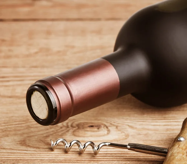 Bottle of wine with corkscrew on wooden background — Stock Photo, Image