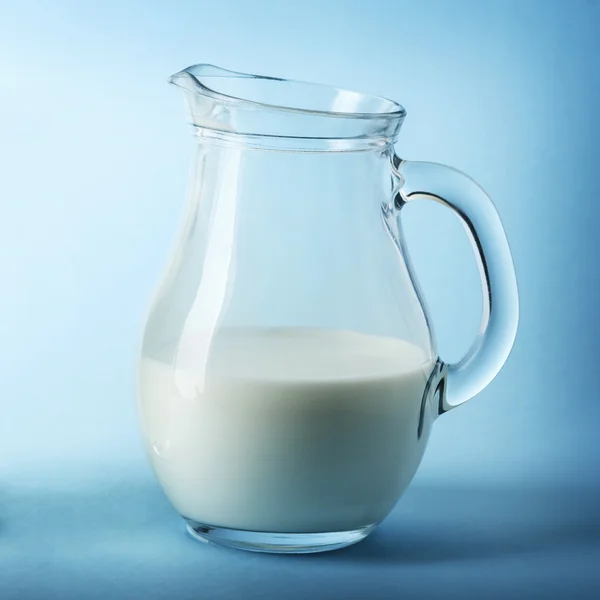 Glass jug of fresh milk on blue background — Stock Photo, Image