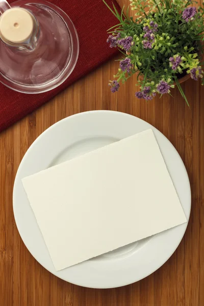 Біла тарілка і квітка на дерев'яному столі — стокове фото