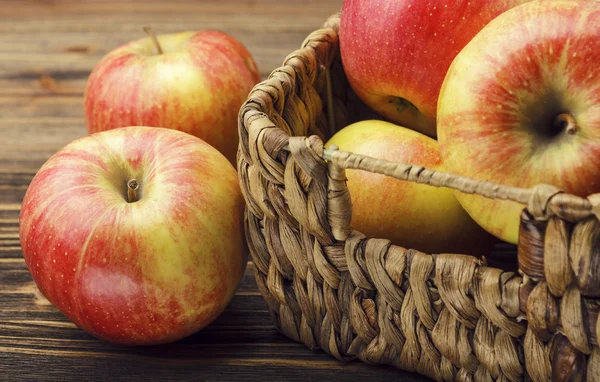 Красные яблоки и корзина на деревянном фоне — стоковое фото