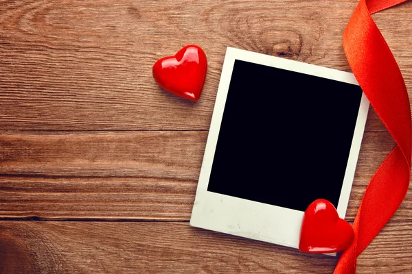 Blank instant photo and small red hearts with ribbon — Stock Photo, Image