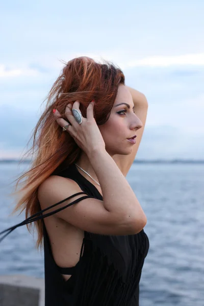 Beautiful woman holding her hair near the sea — Stock Photo, Image