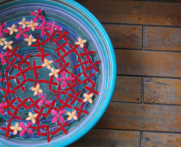 Иксора цветы в миске с водой на деревянном полу
