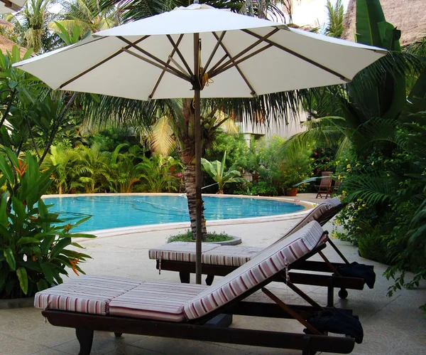 Chairs under umbrella at the poolside — Stock Photo, Image