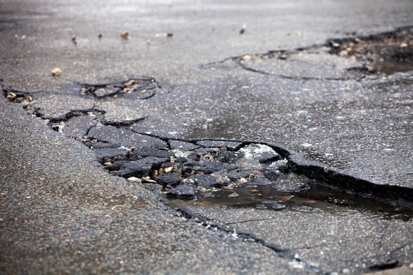 Pavimento quebrado e estrada de asfalto buraco depois do inverno. — Fotografia de Stock