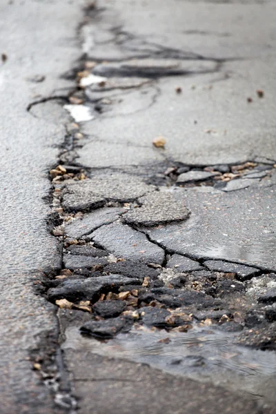 Pavimento quebrado e estrada de asfalto buraco depois do inverno. — Fotografia de Stock