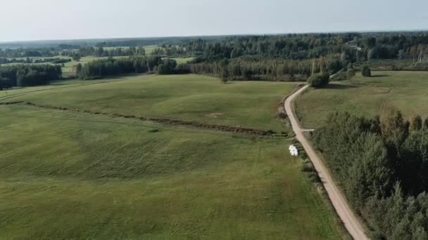 Letecké panorama venkovské silnice procházející zemědělskou půdou a pastvinami v Lotyšsku — Stock video