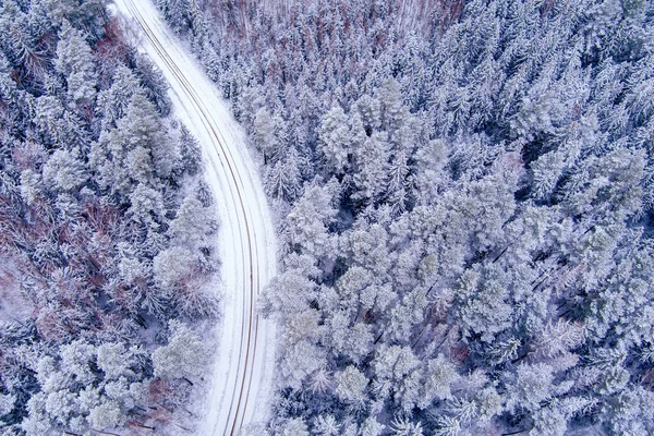 Aerial view of snow covered forest with road as seen from drone