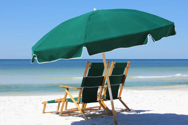 Two chairs and umbrella on white sand beach