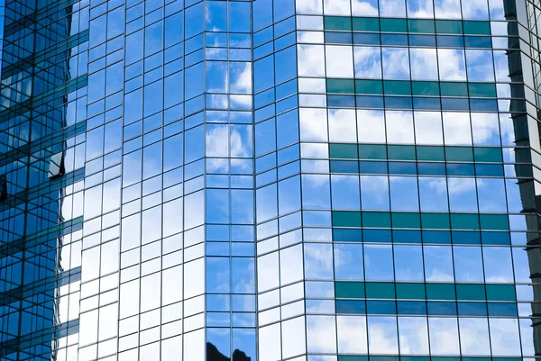 Высотное стеклянное здание с отражением неба и облаков — стоковое фото