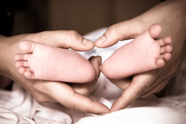 Yeni doğan bebeğin ayakları üzerinde eller — Stok fotoğraf