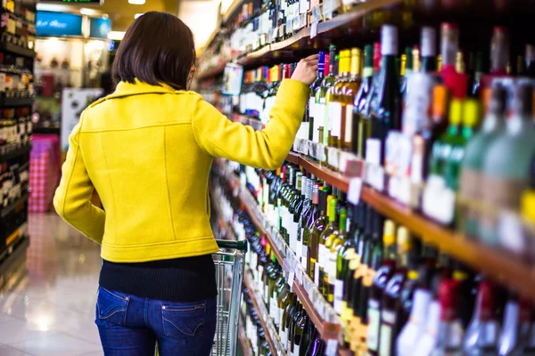 Jeune femme faisant du shopping au supermarché, étagères à vin — Photo