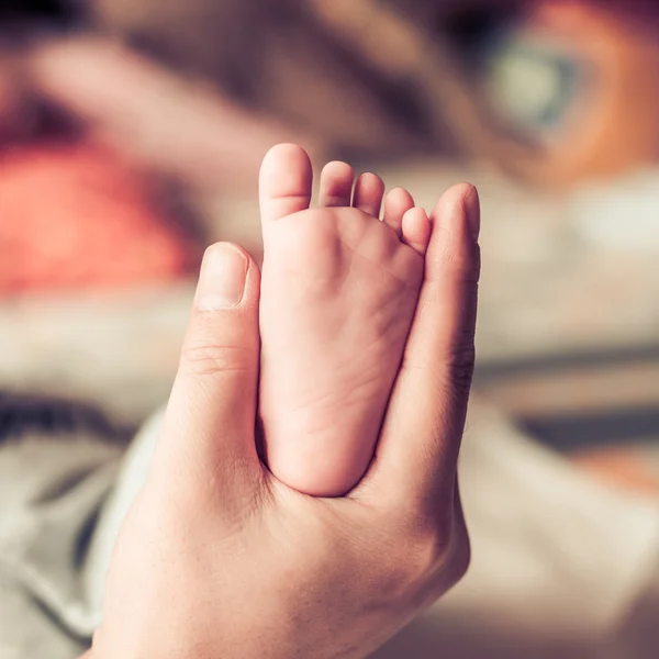 Bebé recién nacido pies en manos femeninas — Foto de Stock