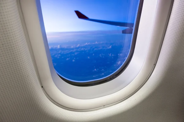 Nuages et ciel vus à travers la fenêtre d'un avion au coucher du soleil — Photo