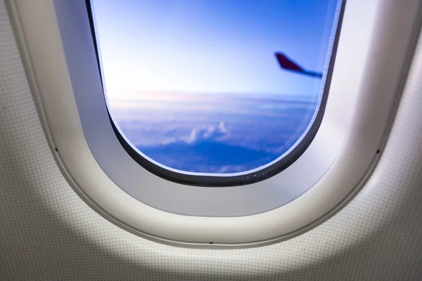 Nubes y cielo visto a través de la ventana de un avión al atardecer —  Fotos de Stock