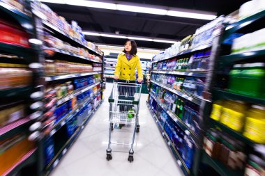 Genç bir kadın süpermarkette alışveriş yapıyor.