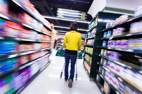 Jeune femme faisant du shopping au supermarché, mouvement flou — Photo