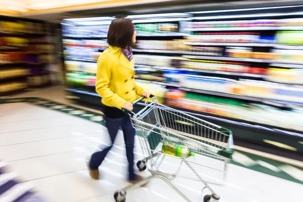 Jeune femme faisant du shopping au supermarché, mouvement flou — Photo