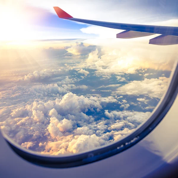 Nubes y cielo visto a través de la ventana de un avión — Foto de Stock